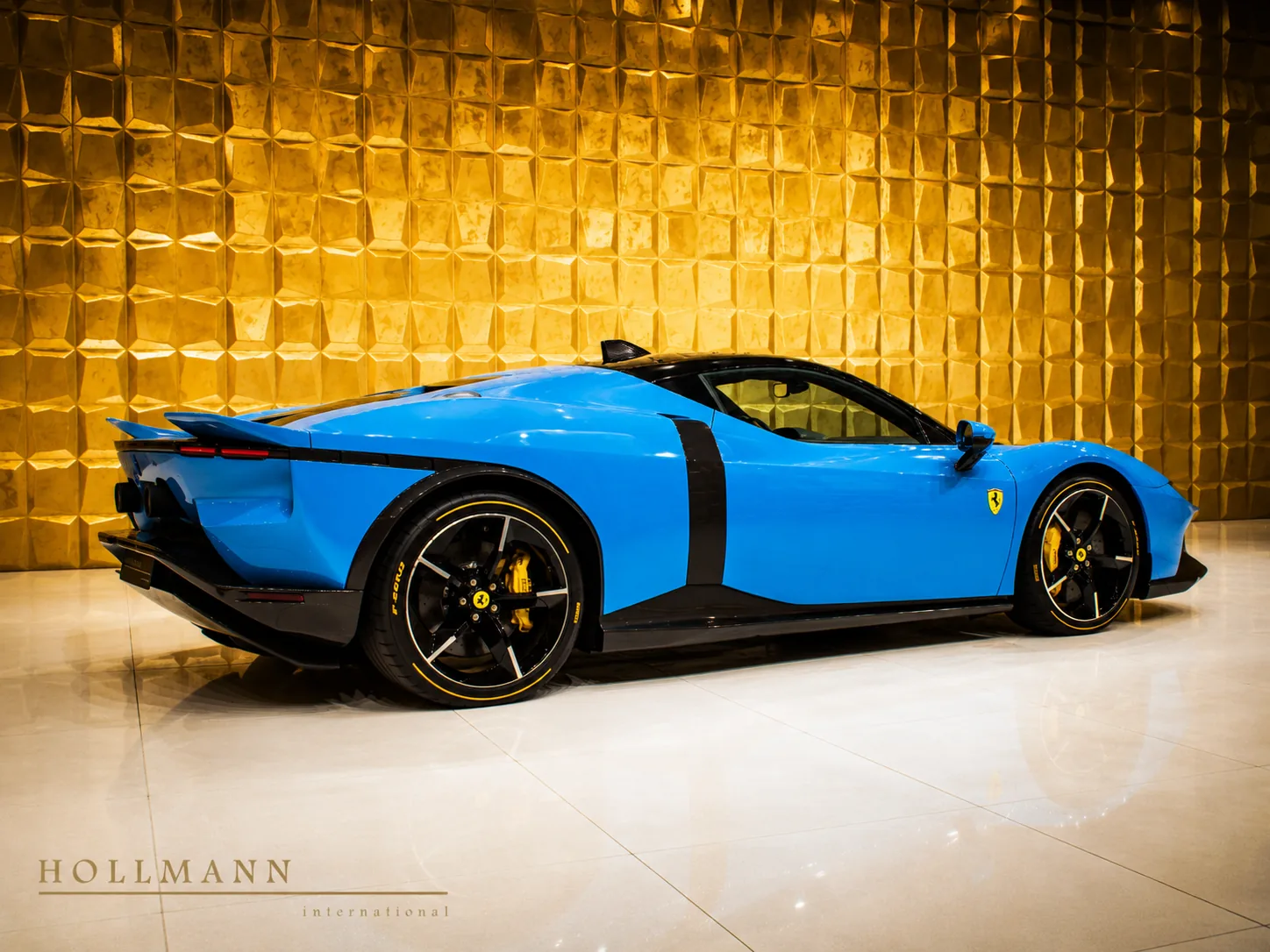 Blue Ferrari displayed in front of a sculpted golden wall
